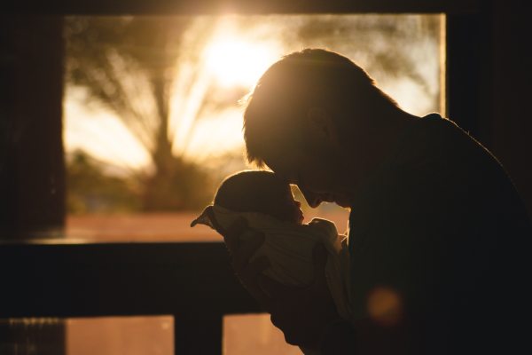 photo of man holding baby at sunrise