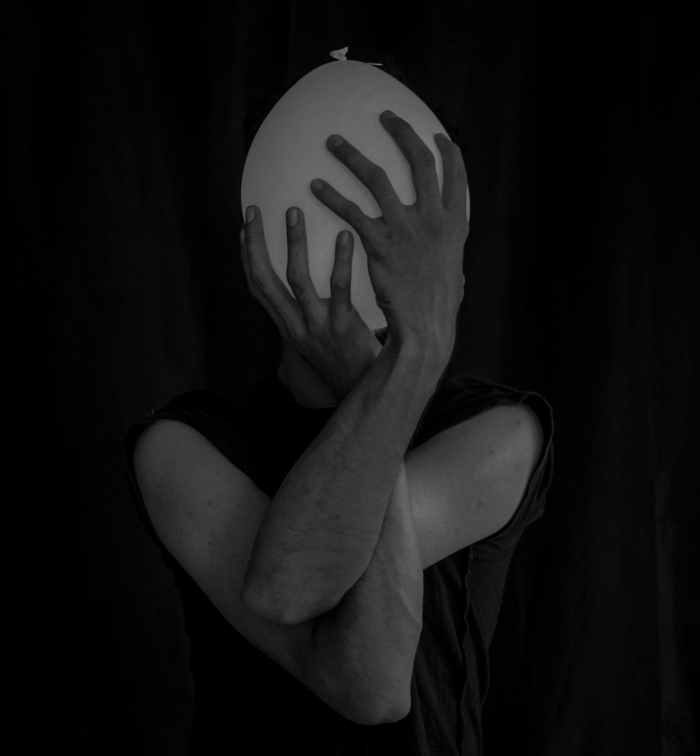 black and white photo of a man holding a ballon over his face