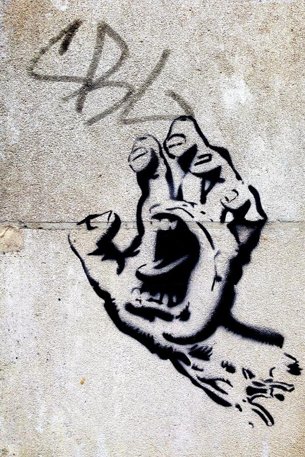 photo of grafitti hand drawing on cement wall